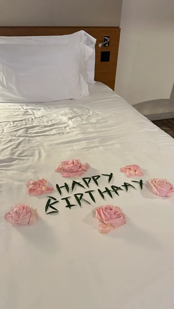 Happy birthday spelled in leaves with rose petals on the bed at Centara Grand Ladprao