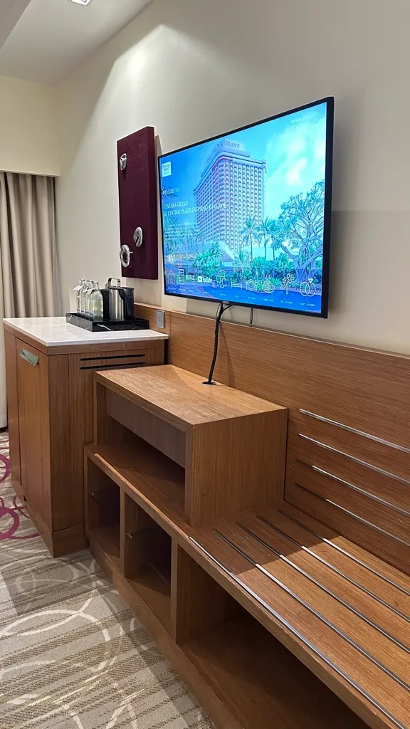 Wall-mounted TV, coffee station and wooden bench in a room at Centara Grand Ladprao
